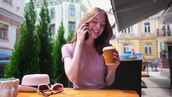 Young Woman Talking on the Phone in a Cafe on a Summer Terrace