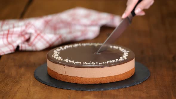 Confectioner hands cut by knife chocolate mousse cake.