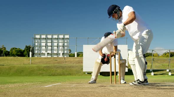 Wicket keeper collecting cricket ball behind stumps on cricket field