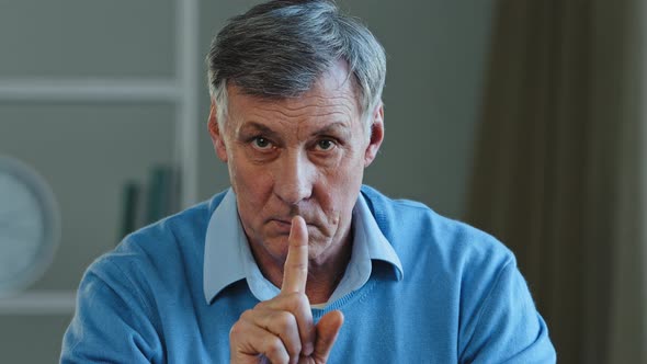 Closeup Old Caucasian 60s Man Holding Index Finger Near Mouth Stop Talking Hush Gesture Silence Sign