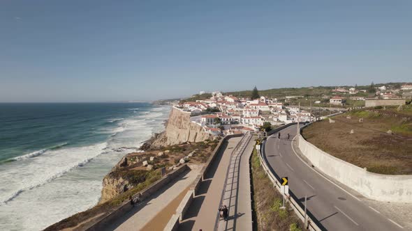 People walking on walkway along seaside cliff, coastal road near Azenhas do Mar, Portugal