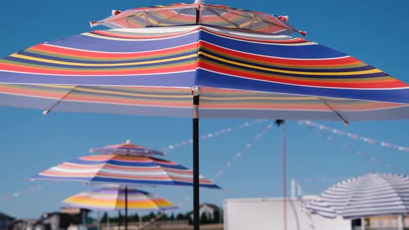 Bright Colored Beach Umbrellas in the Wind Against the Blue Sky