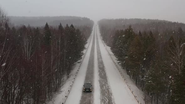 A Passenger Car Drives Along a Snowcovered Track During a Snowfall