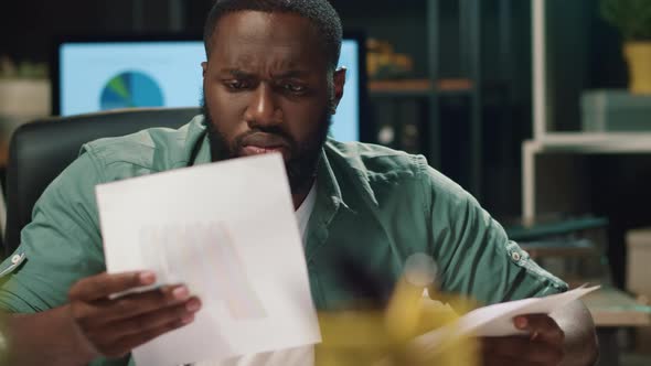 Closeup Disappointed Afro Business Man Looking Papers in Hipster Office.