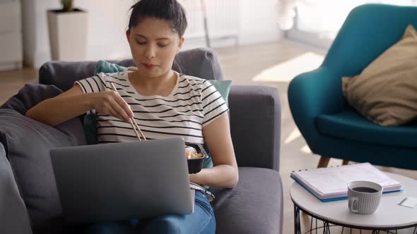 Handheld video of smiling Asian woman eating during video conference 