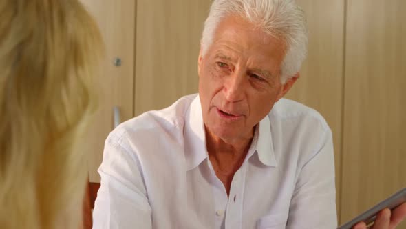 Senior man with digital tablet interacting to senior woman