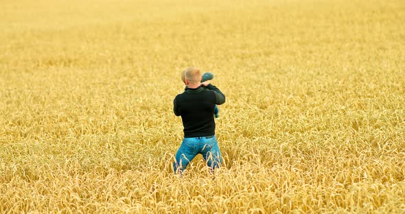 Dad is Circling His Son in a Wheat Field the Child is Happy and Laughing