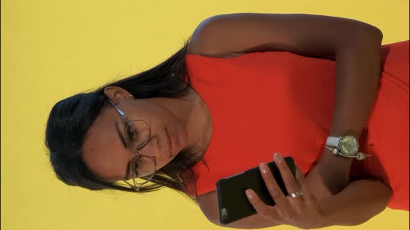 Multiracial Pretty Woman Looking Surprised at Smartphone on Yellow Background.