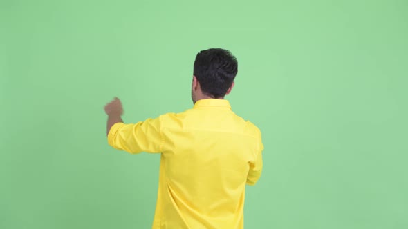 Rear View of Young Hispanic Businessman Directing and Pointing Finger