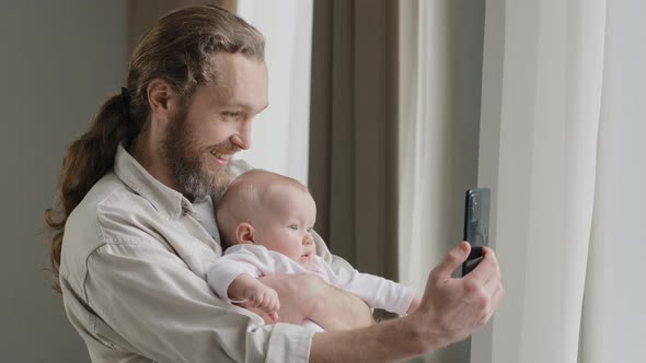 Happy Smiling Caucasian Father Adult Daddy Holding Newborn Child at Home Standing Near Window Dad
