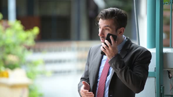 Young Happy Hispanic Businessman Talking on the Phone Outdoors