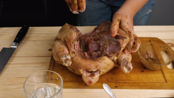 Close-up of a woman's hands salting and seasoning a chicken