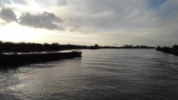 Industrial Barge Ship With Bulk Cargo Cross Oude Maas River At Sunset In Netherlands. - aerial