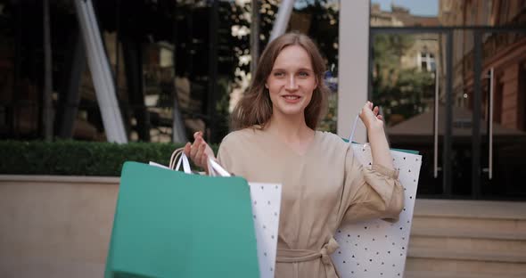 Young Woman with Shopping Bags Walking in a City. A Girl Walks Along After Shopping with Full Bags