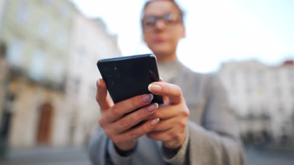 Woman Walking Down an Old Street Using Smartphone at