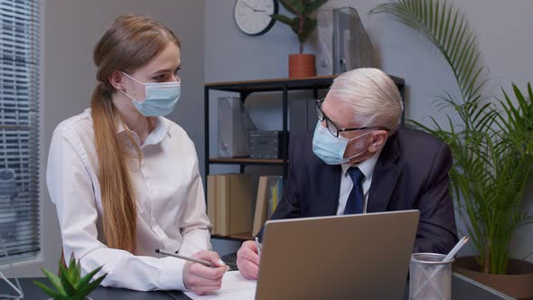 Elderly Man Boss with Woman Secretary in Medical Mask Working in Office During Coronavirus Pandemic