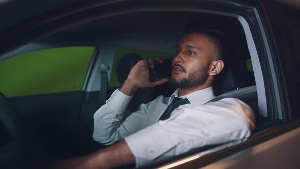 Overexerted Businessman Sitting In The Driving Seat Talking To Someone On Phone