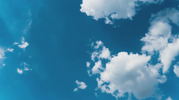 White Fluffy Clouds Slowly Float Through the Blue Daytime Sky Timelapse