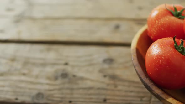 Video of fresh tomatoes in bowl with copy space over wooden background