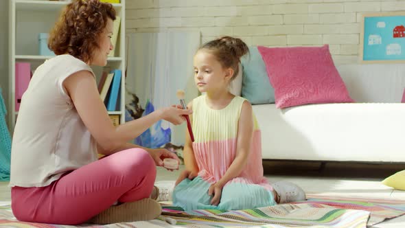 Mom Teaching Little Daughter How to Use Face Powder alt