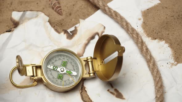 Man Hand Putting Gold Compass on Burnt Maps on Sand Background Closeup Golden Compass in Human Palm