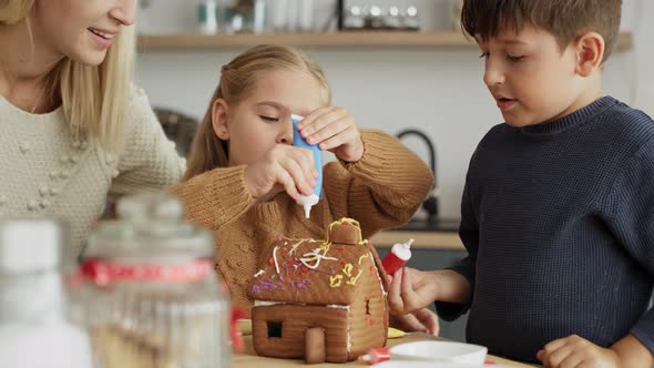 Video of cheerful children decorating homemade gingerbread house. Shot with RED helium camera in 8K.