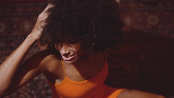 Woman With Afro Hair In Orange Dress Smiling To Camera