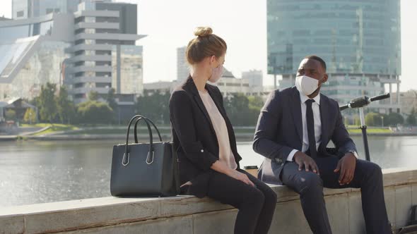 Business Couple In Protective Masks Sitting By Water