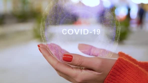 Female Hands Holding Hologram COVID-19