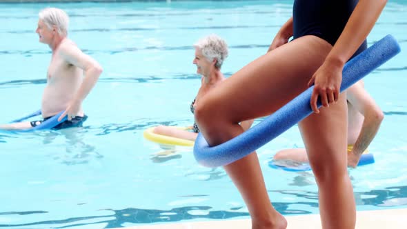 Swim trainer assisting seniors in performing exercise