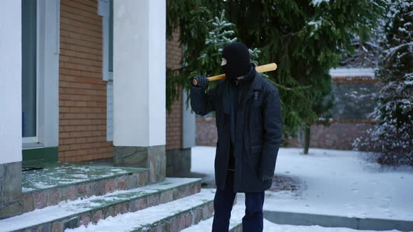 Confident Male Burglar Standing with Baseball Bat on Winter Yard Outdoors Looking Around