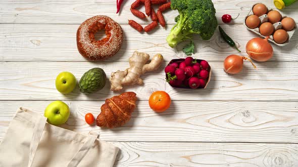 Grocery bag with fruits, vegetables, bread, bottled beverages on wooden table. Top View. Stop Motion