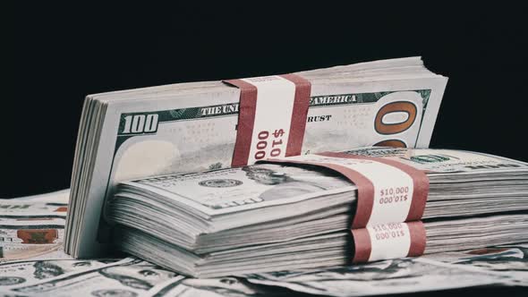 Bundles of Dollars Lying on a Pile of Money and Rotate on Black Background