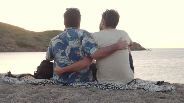 Unrecognizable Gay Male Couple Hugging While Watching a Sunset By the Sea