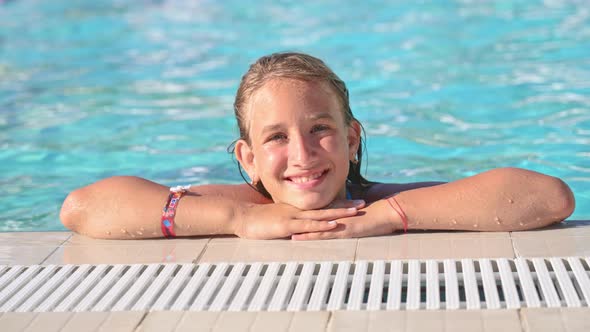 Close Up of Caucasian Beautiful Teenage Girl Leaning on Her Hands and Hanging on Side of Pool and