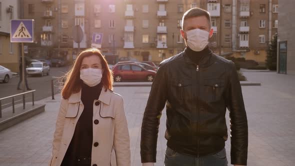 Young Couple in Protective Medical Masks Crossing Hands Near Chest. Coronavirus.