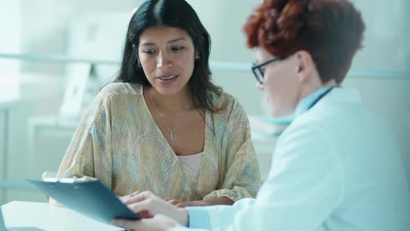 Beautiful Hispanic Woman Talking with Female Doctor in Clinic