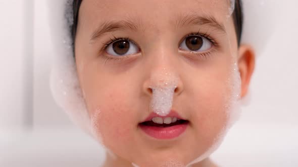 Three Year Old Child with Big Brown Eyes Is Sitting in a White Bathroom