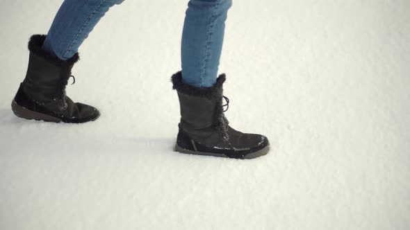 Legs Footprints In Winter Boots Walking On Snow. Woman Legs Walking In Snow.