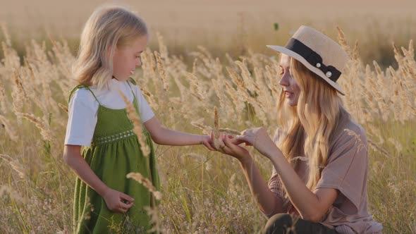 Caucasian Young Mother Woman in Hat Sits in Field with Little Girl Cute Daughter Child Holds Baby