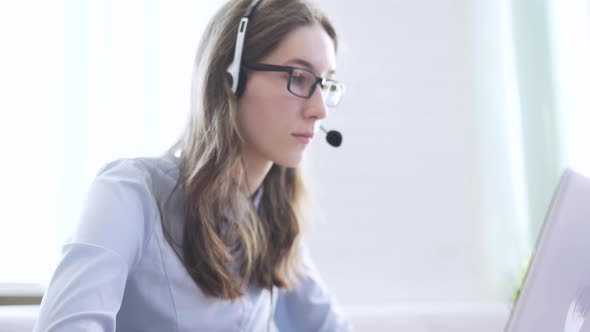 Serious Call Center Operator in Wireless Headset Talking with Customer Close Up