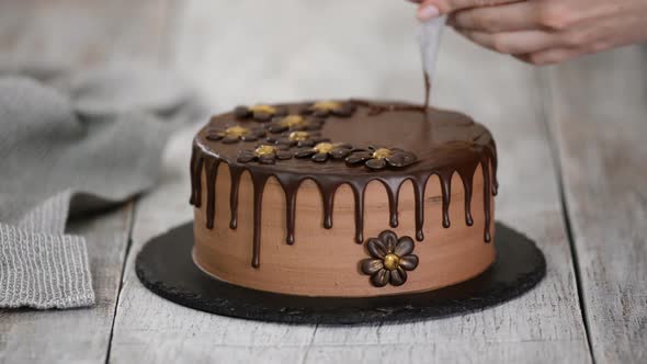 Confectioner-baker decorate beautiful cream cake with melted chocolate.	