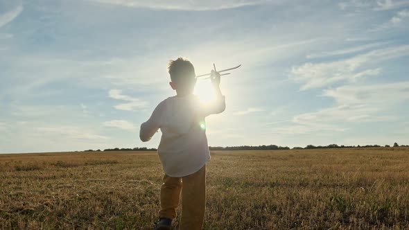 Boy Runs in Field with Toy Plane in Hand and Flies Airplane