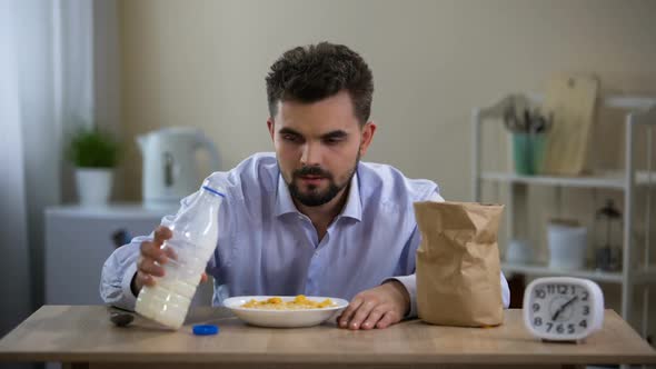 Single Young Man Eating Flakes Milk With Disgust in Morning, Bachelor Nutrition