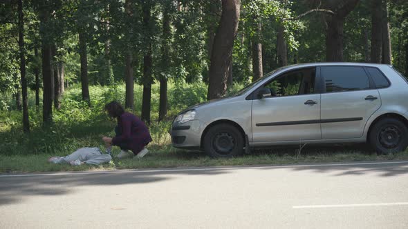 Wide Shot Stressed Driver Running to Knocked Down Woman Lying on Roadside Checking Pulse Holding