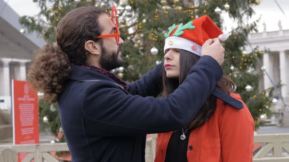 Christmas Time: Funny lovers wearing christmas accessories and kissing