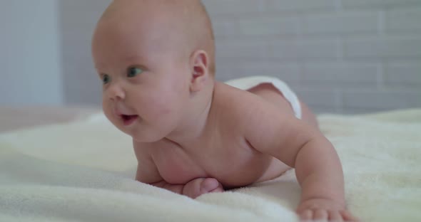 Funny Portrait of Newborn Baby Looks Around Surprisely on a Bed