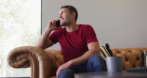 Happy caucasian man spending time at home and using smartphone