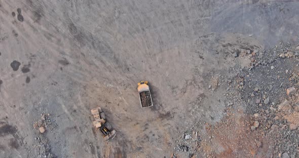 Excavator Loads the Mined Rock in the Dump Truck for Stone Crusher Machine During Earthmoving Works