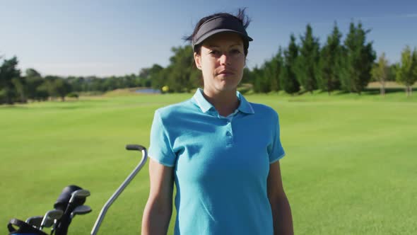 Portrait of female caucasian golf player crossing her arms while standing at golf course